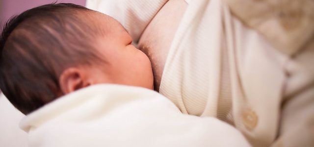 Kobieta karmi małe dziecko w biustonoszu do karmienia
